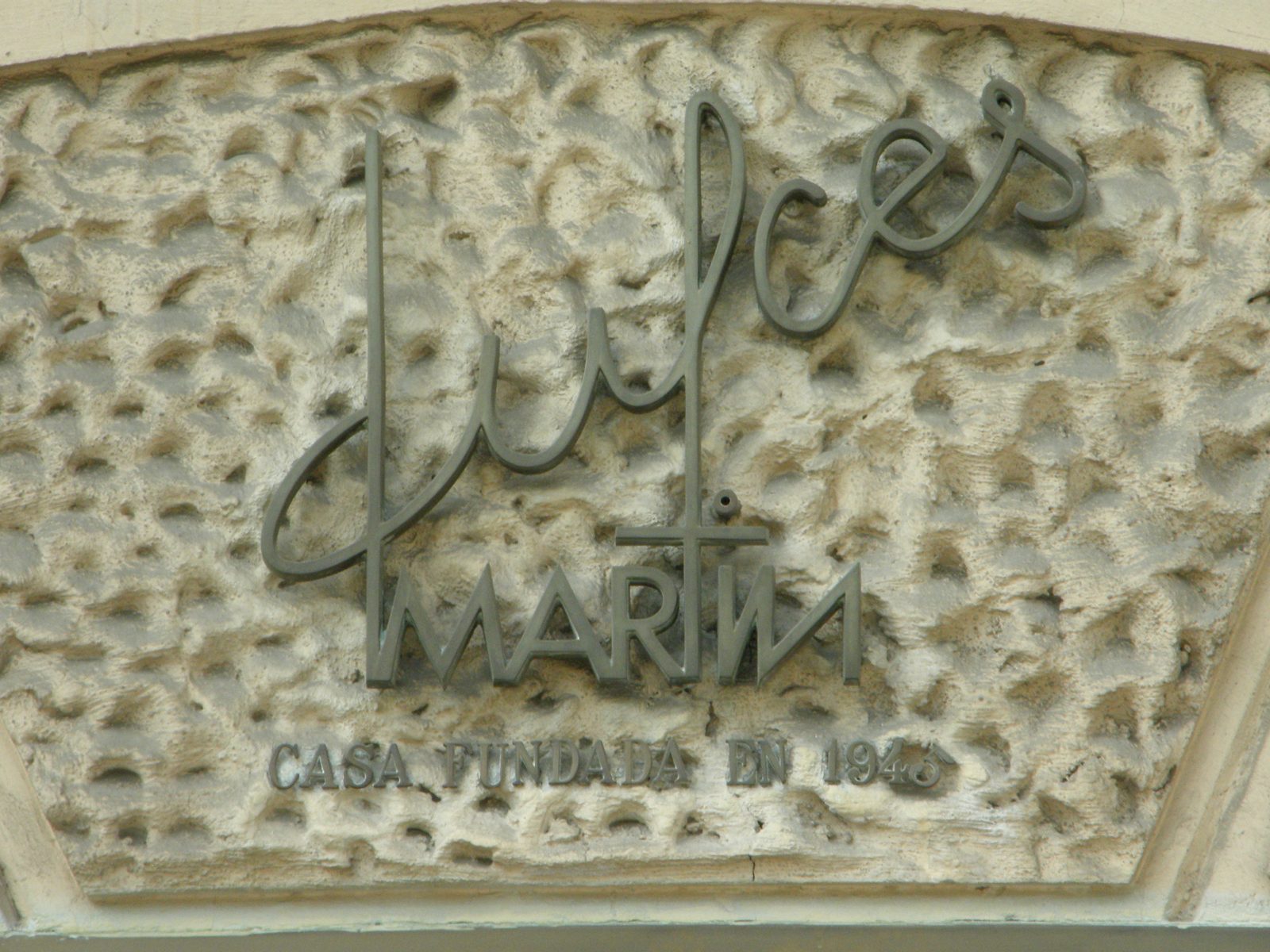 でこぼこした石の壁に、金属の筆記体で dulces MARTIN の文字。下に CASA FUNDADA EN と年