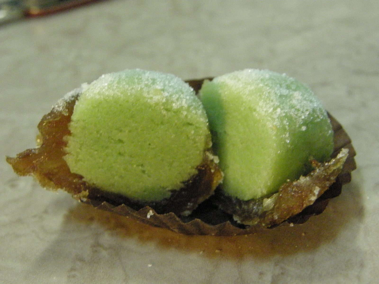 紙の器にのった二つに割れた緑色の菓子。断面まで一様に緑色で、表面に砂糖の粒がついている