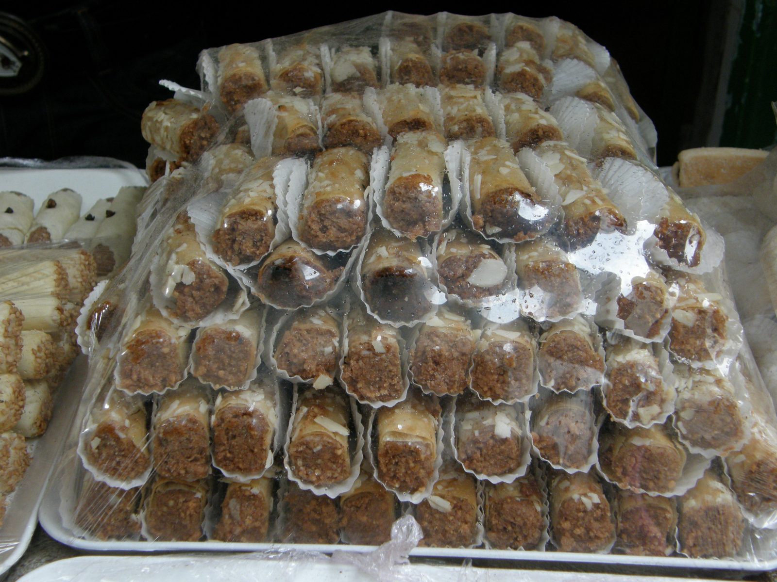 透明な袋をかぶせた盆に、白い紙のカップに入った、断面に茶色の詰め物が見える筒形の菓子が何段も積まれている