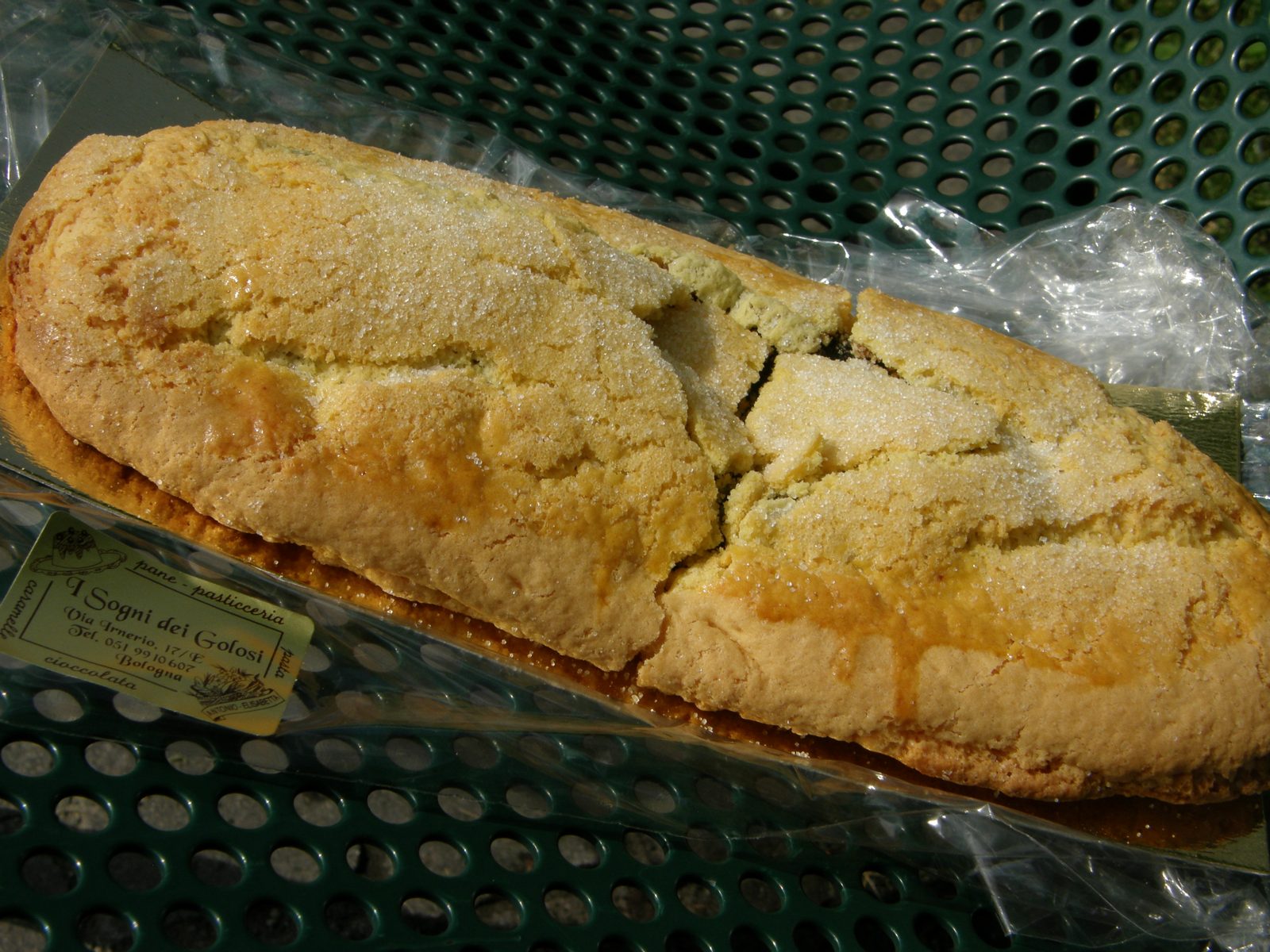 透明な袋の上に置かれた、粒の砂糖をまぶした細長い焼き菓子。ひびの入った表面