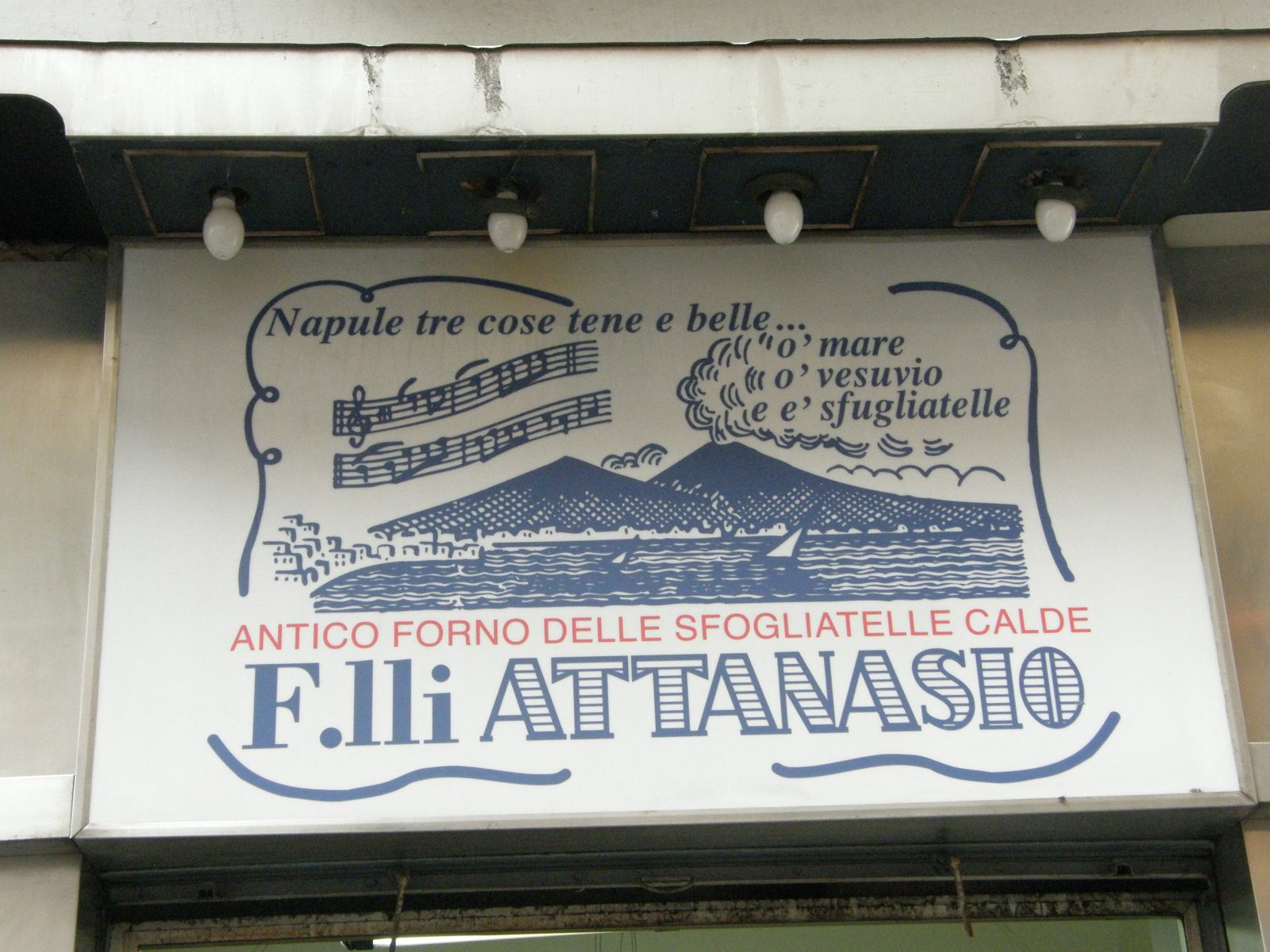 白い看板。青い字で店名 F.lli ATTANASIO、ヴェスヴィオ山と海の絵、楽譜の絵、ナポリの言い回しが書かれている