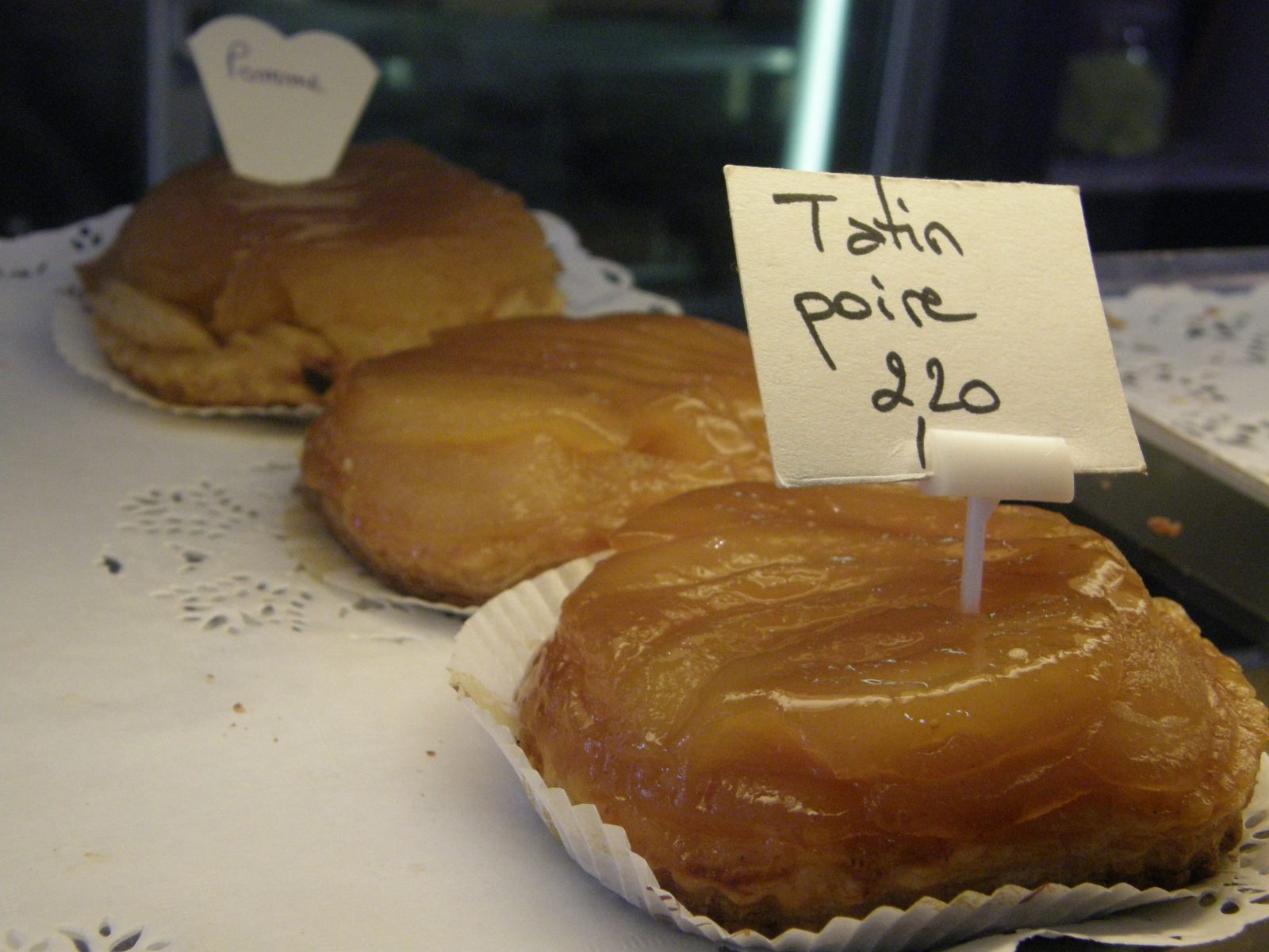 菓子屋の台に並ぶ二つのタタンと、Tatin poire 2,20 と書かれた手書きの札