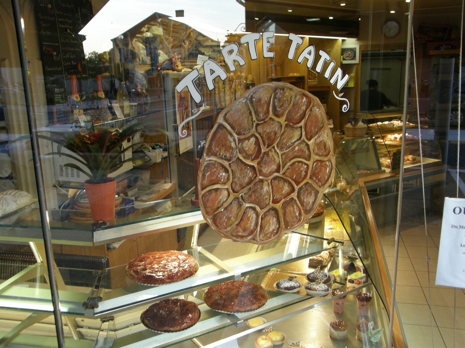 菓子屋のウィンドウ越しに、TARTE TATIN と書かれた看板と、タタンをかたどった飾り