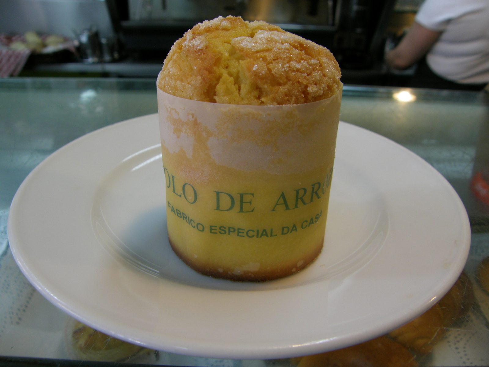 紙の帯を巻いた、筒形の小さな焼き菓子。帯に「BOLO DE ARROZ」の文字
