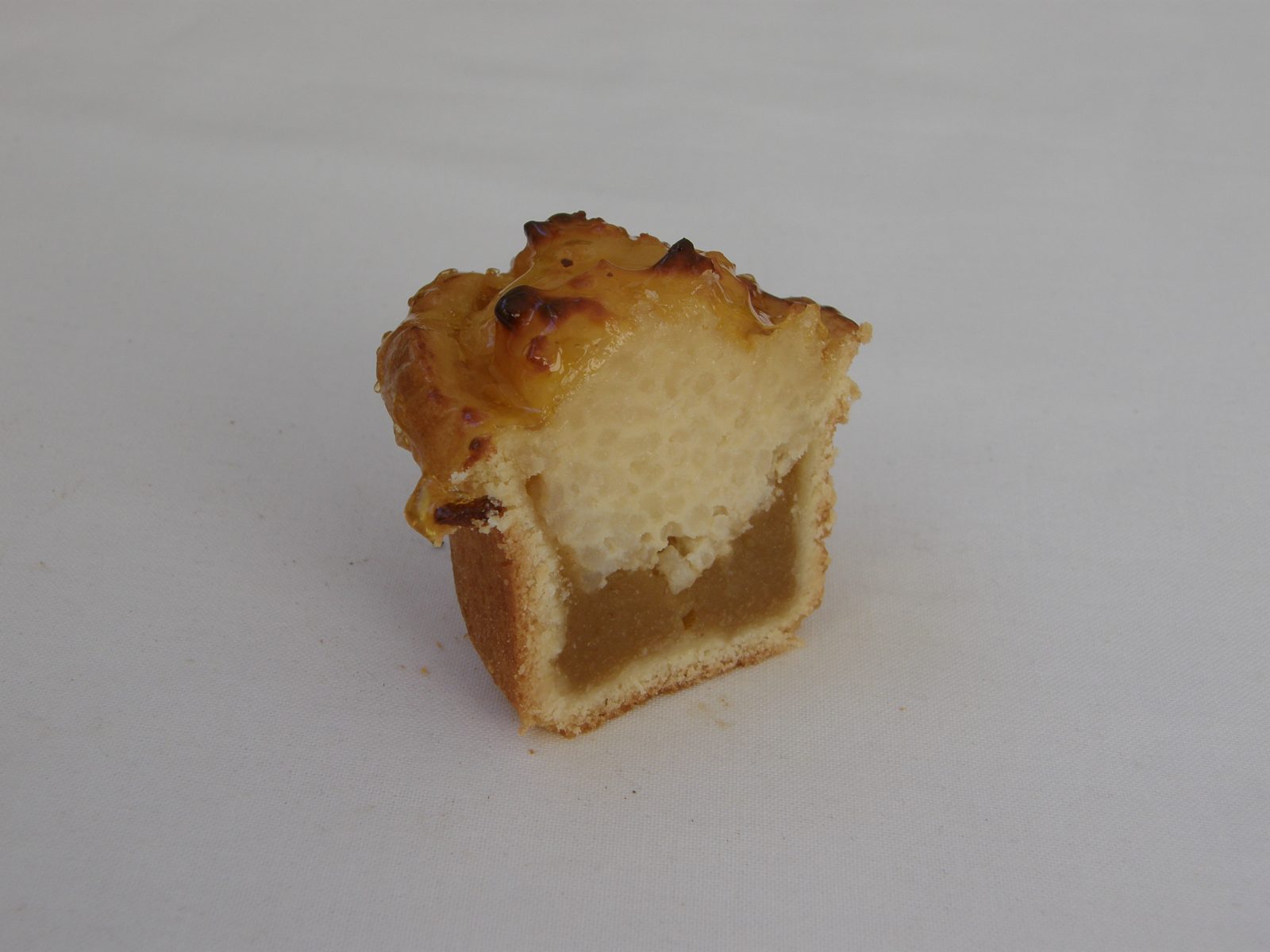 切ったタルトの断面。底の生地の上に茶色のリンゴのピュレの層、その上に白い米のクリームの層、表面に焼き色
